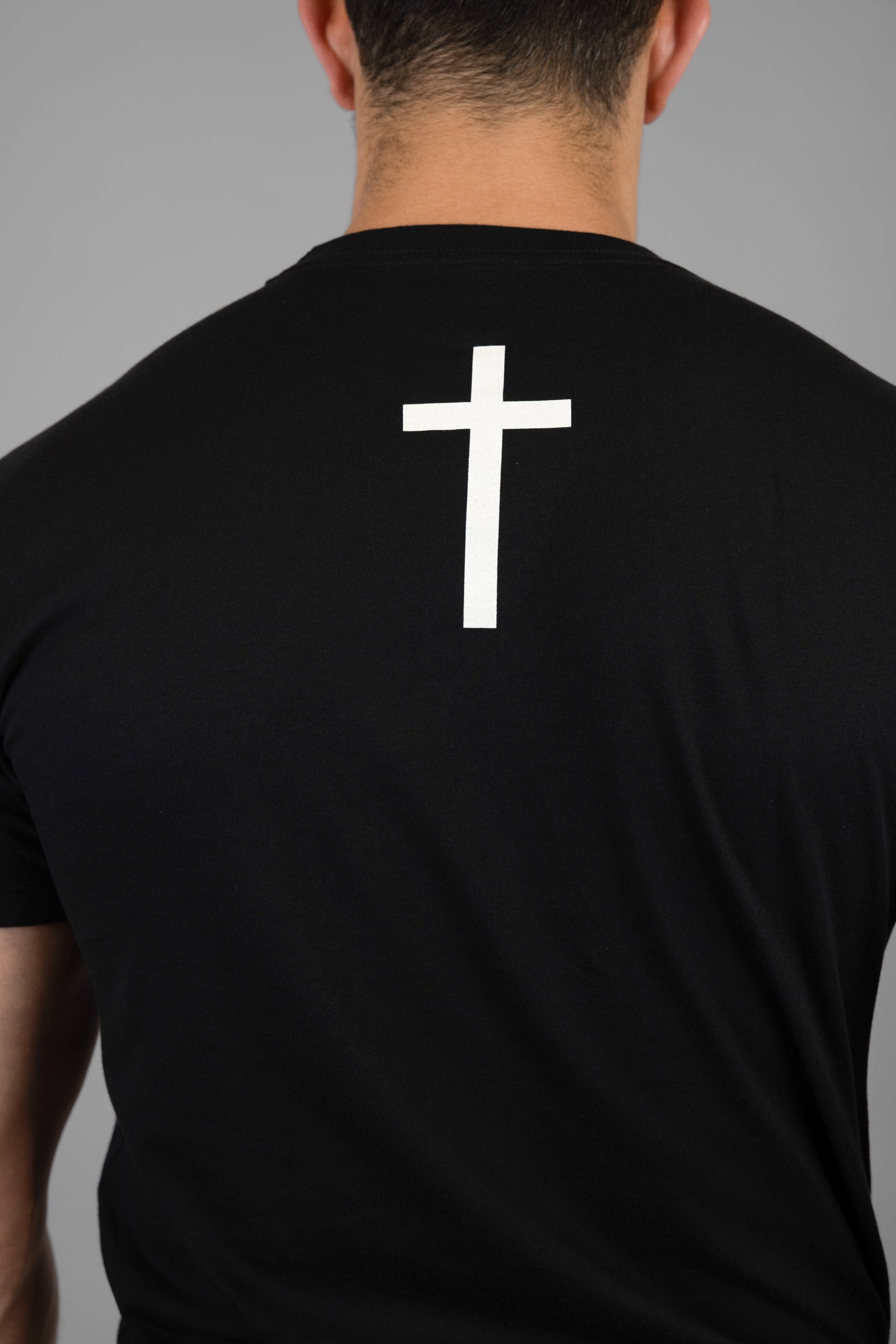 Man wearing black tee with white cross on back