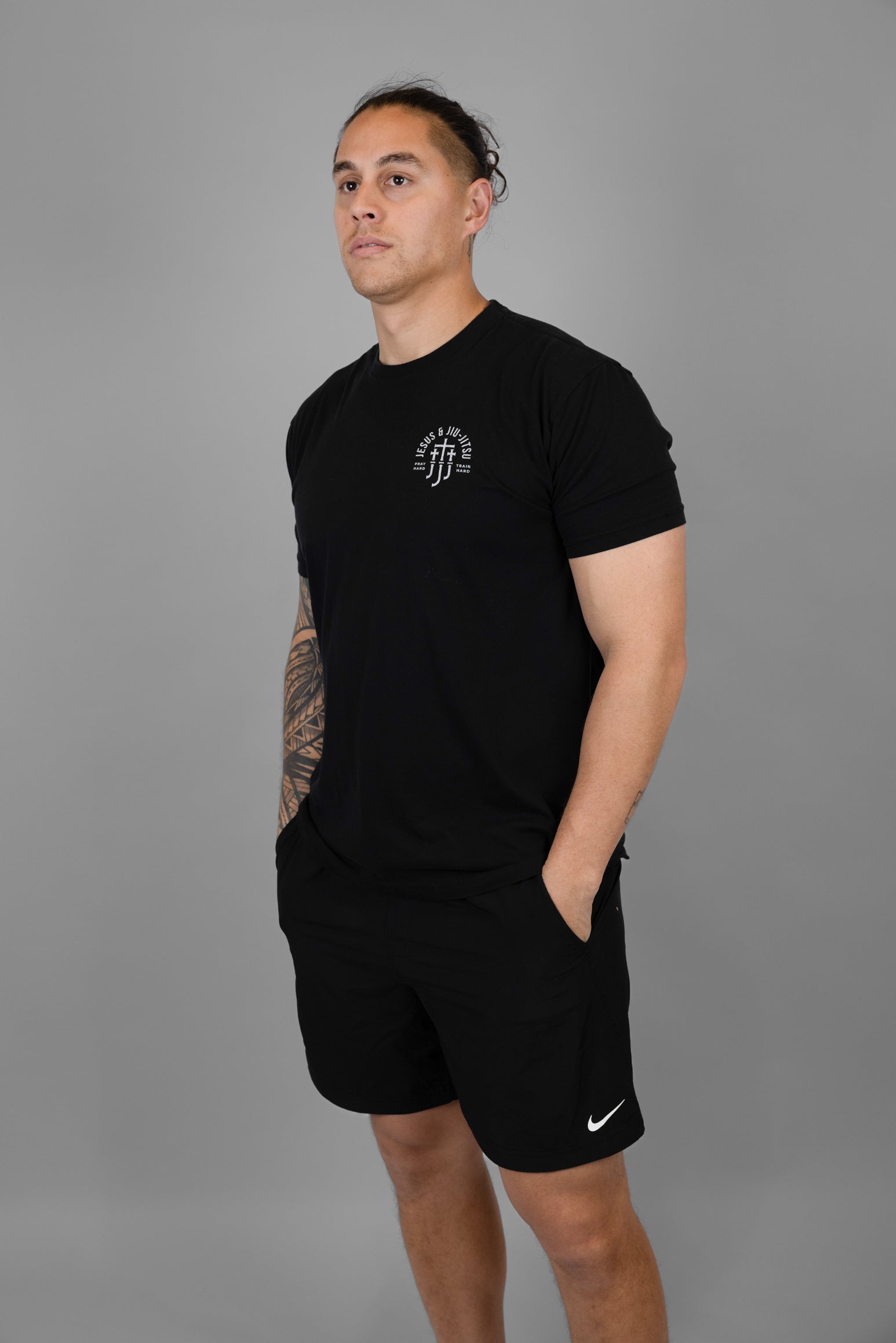 Man wearing a black t-shirt with JJJ logo and shorts with a logo on a gray background