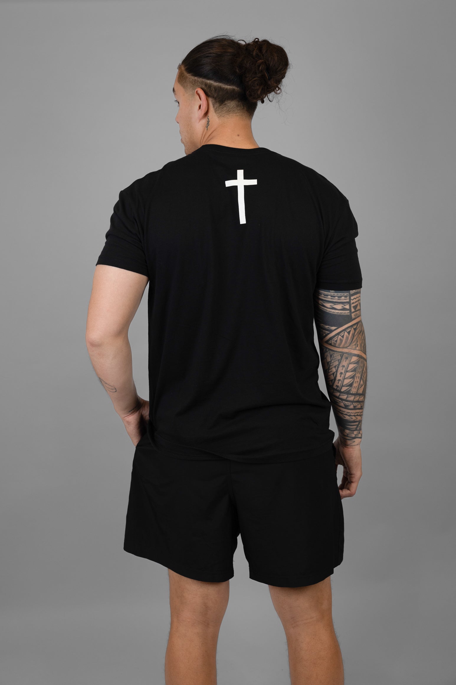 Man wearing black tee with white cross on back