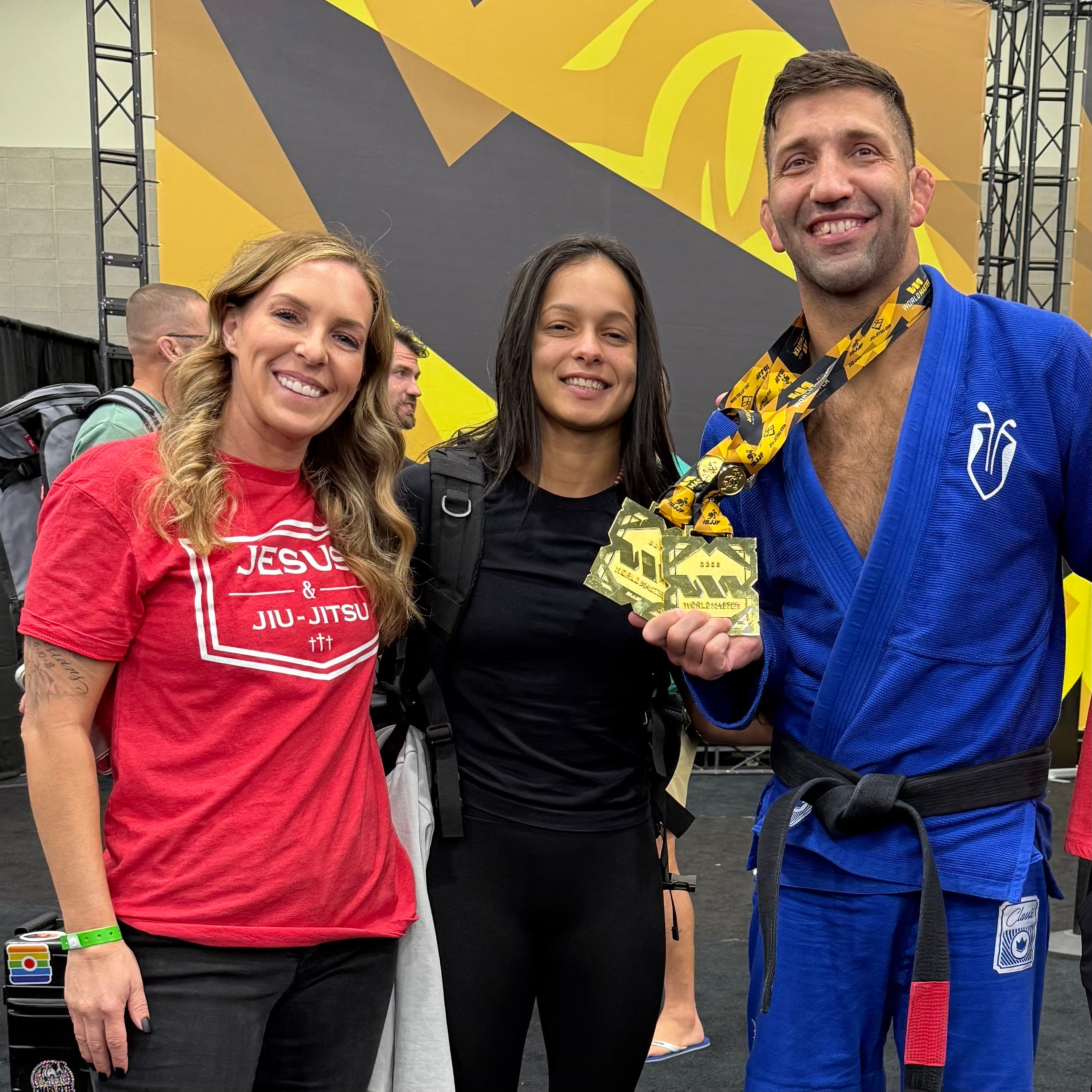Woman standing with group wearing  red shirt with white JESUS & JIU-JITSU logo