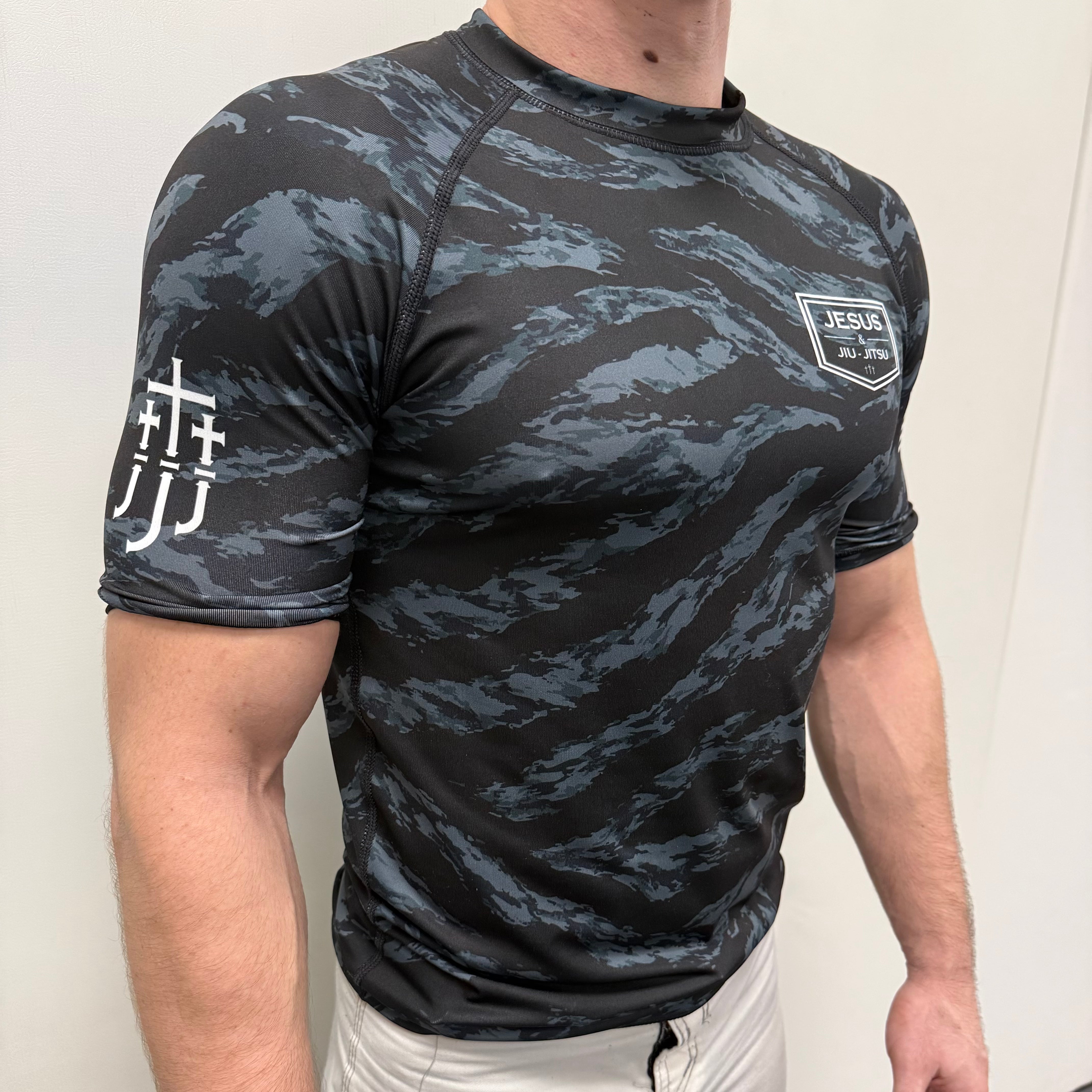 Man wearing black tiger camo rashguard with JJJ logo on left chest and right shoulder