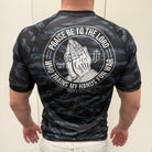 Man wearing black tiger camo rashguard with prayer hands graphic on back