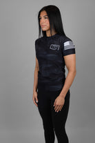 woman wearing black tiger camo with JJJ logo on left chest and American flag on left shoulder