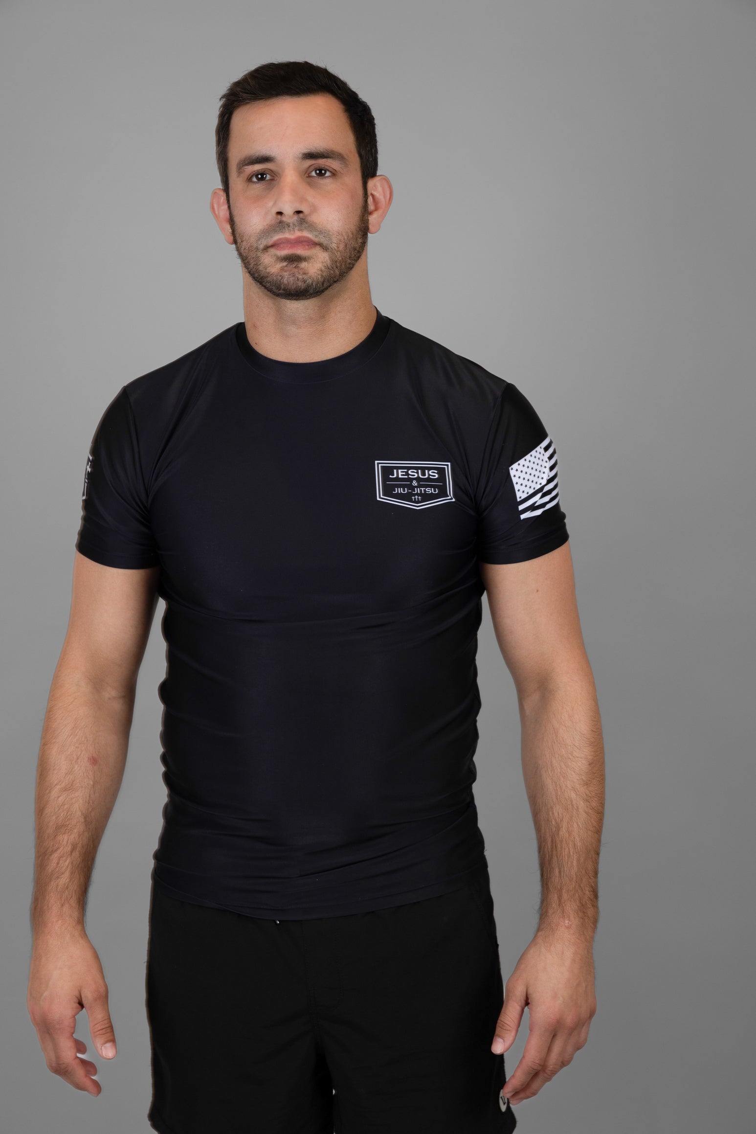 Man wearing black Rashguard with "JESUS & JIU-JITSU" logo on left chest