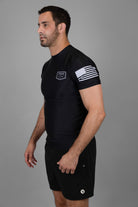 Man wearing black Rashguard with "JESUS & JIU-JITSU" logo on left chest and American flag on left shoulder