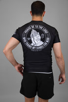 Man wearing black rashguard with prayer hands graphic on back and American flag on left shoulder