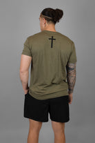 rear view of man wearing green tee with black cross