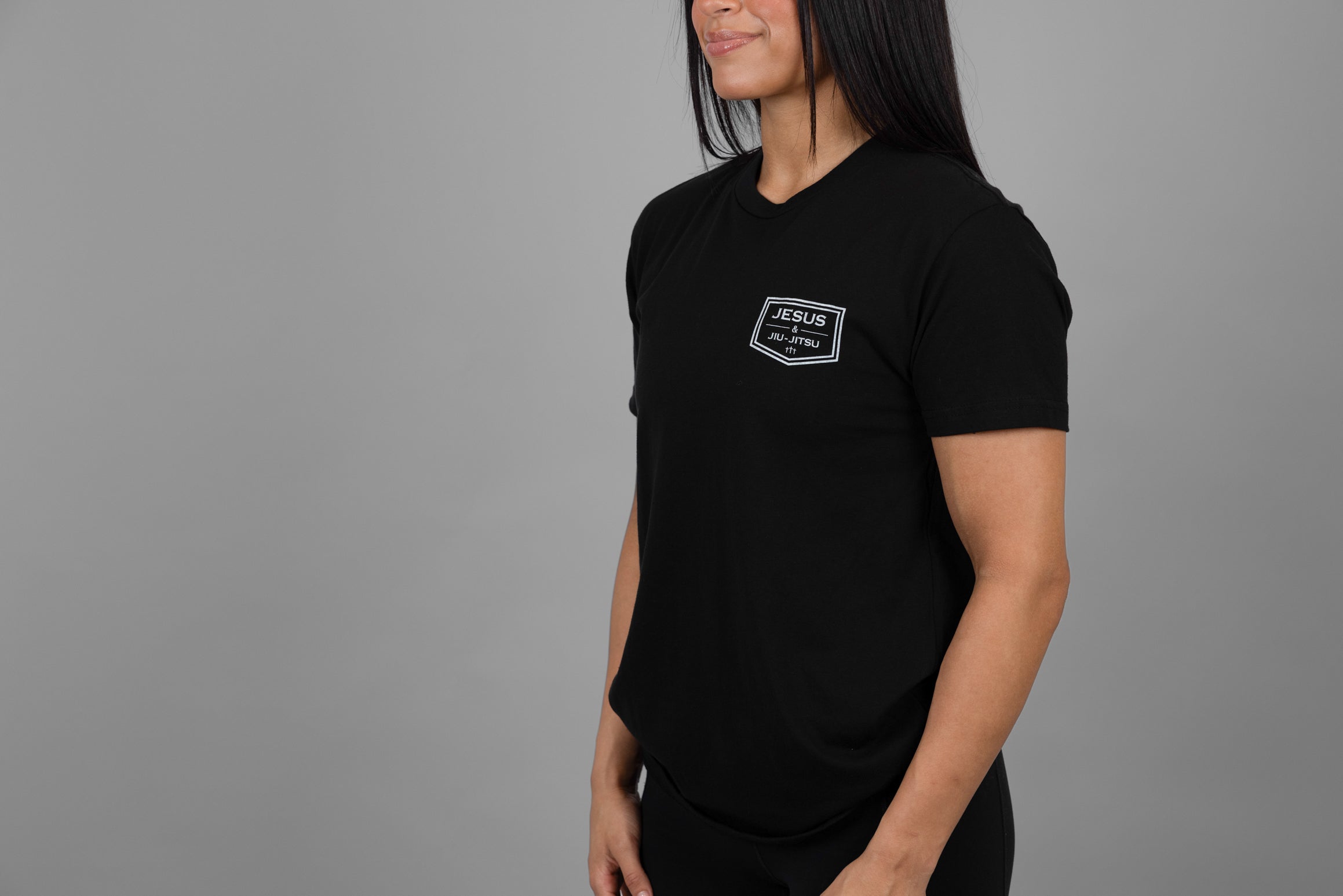 Person wearing a black t-shirt with "JESUS & JIU-JITSU" logo on left chest