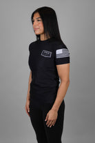 Woman wearing black Rashguard with "JESUS & JIU-JITSU" logo on left chest and American flag on left shoulder