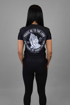 Woman wearing black rashguard with prayer hands graphic on back and American flag on left shoulder