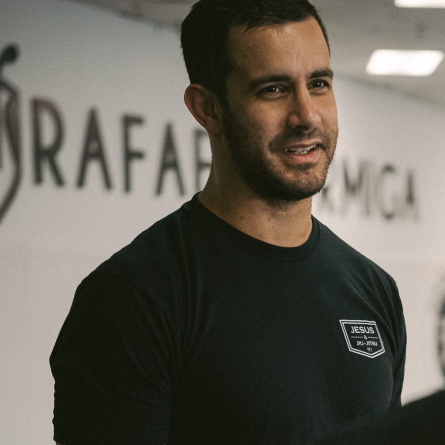 Person wearing a black t-shirt with "JESUS & JIU-JITSU" logo on left chest