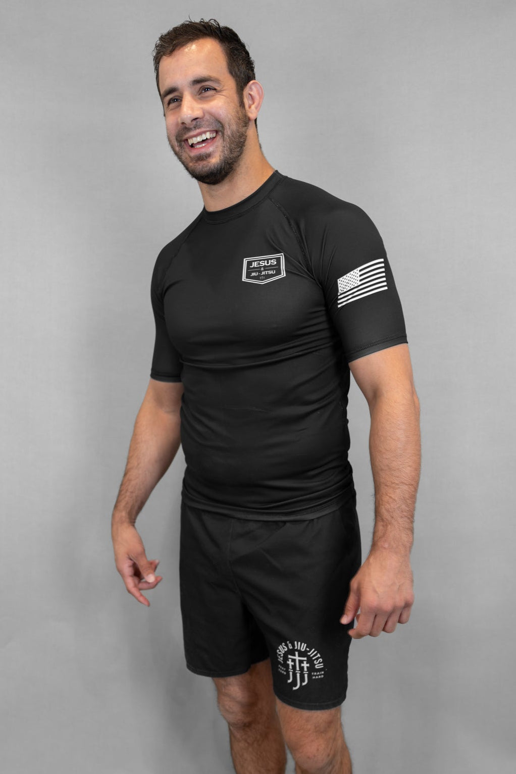 Man wearing black rashguard with JJJ logo on left chest and flag on left arm