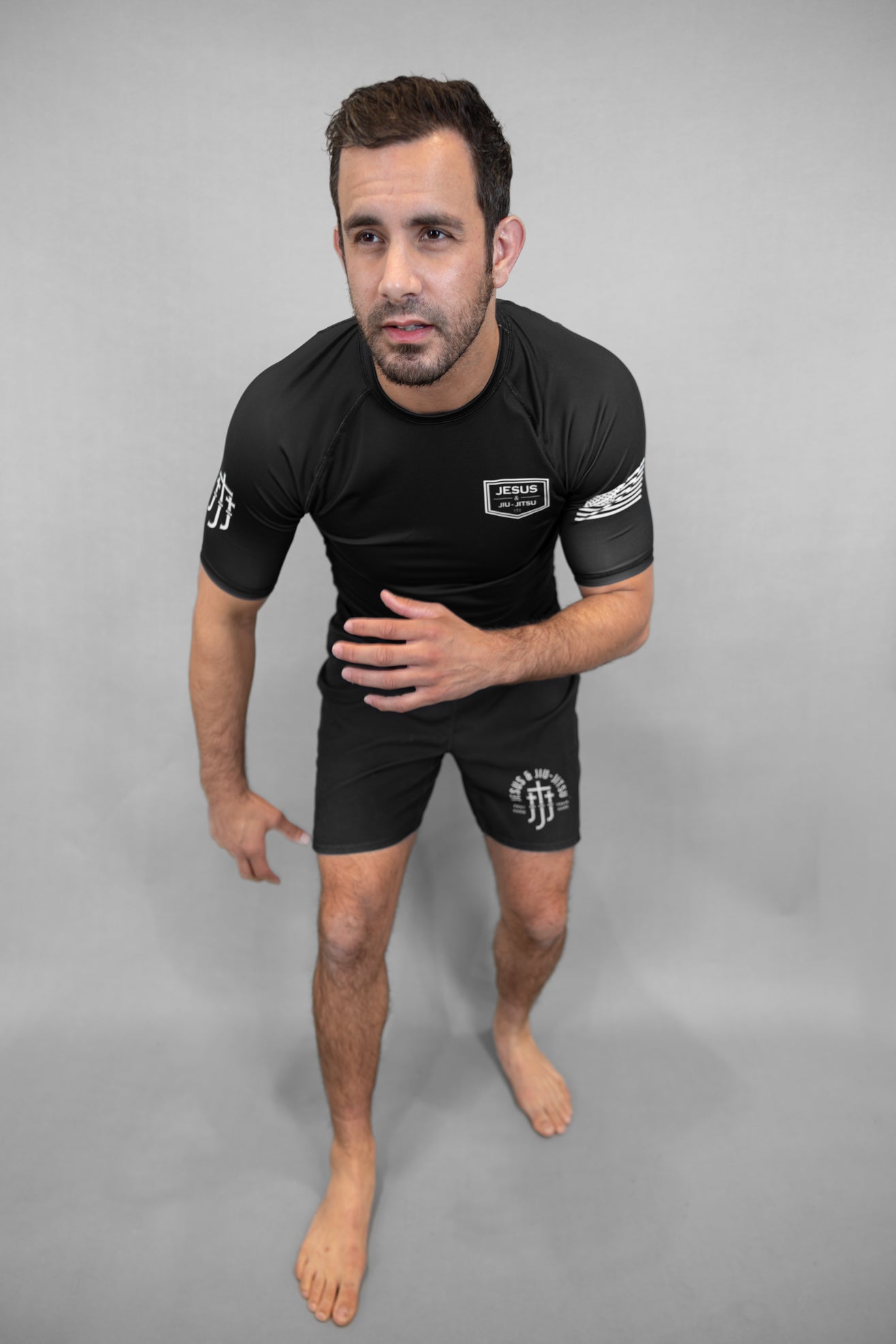 Man wearing a black rashguard with JJJ logo on a gray background