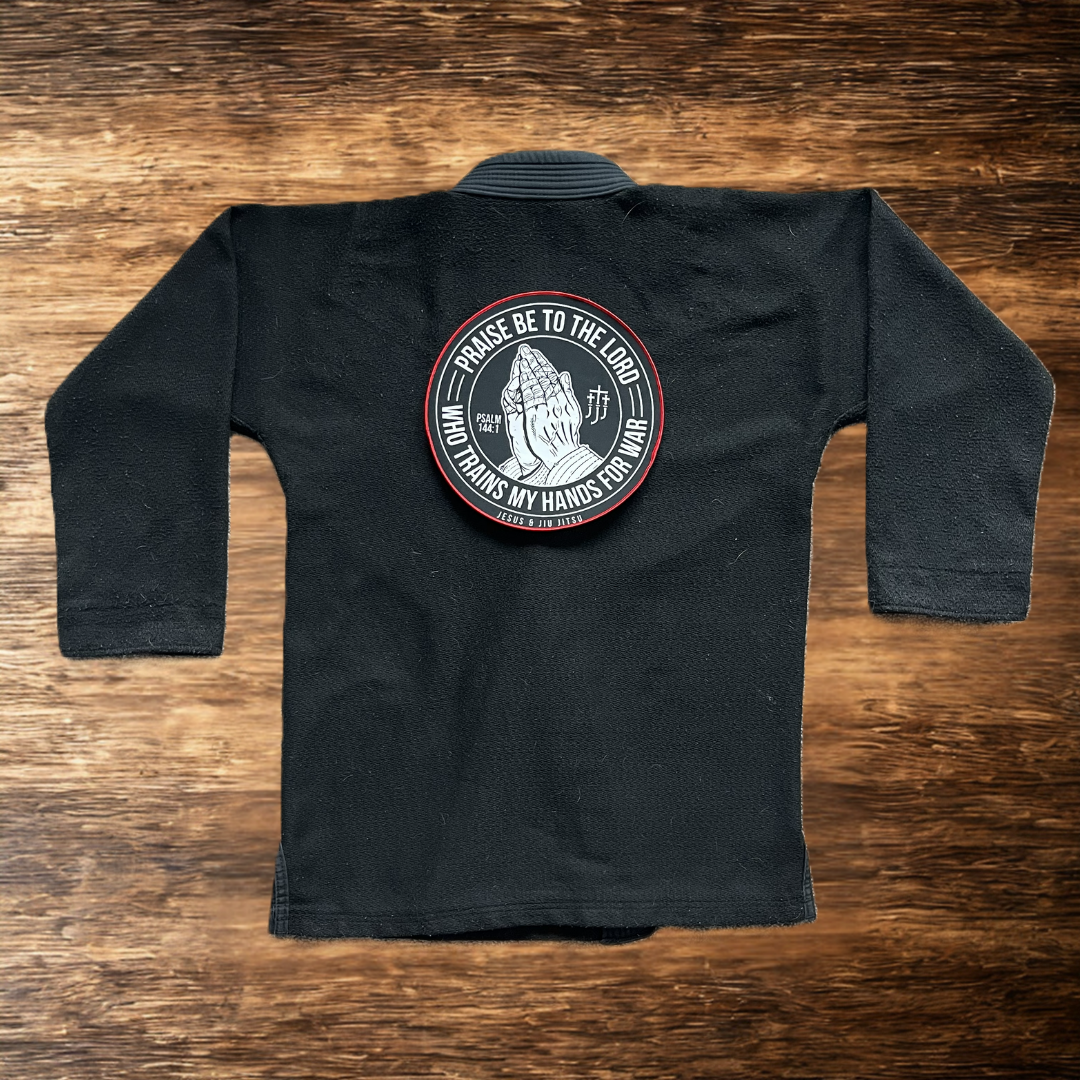 10in Patch with praying hands design and "PRAISE BE TO THE LORD WHO TRAINS MY HANDS FOR WAR" text on a black gi