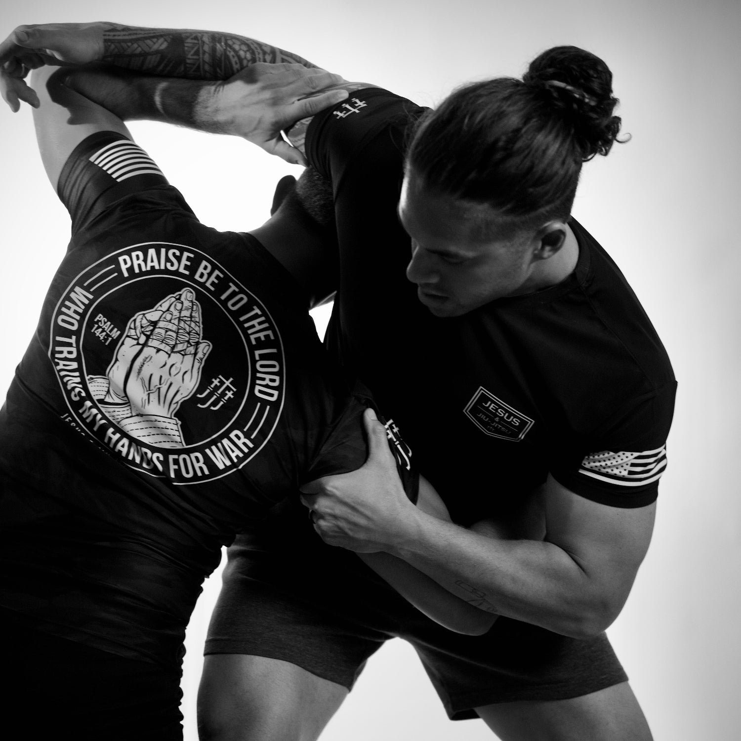 Two individuals in black athletic wear with JJJ branding and text, performing a martial arts move.