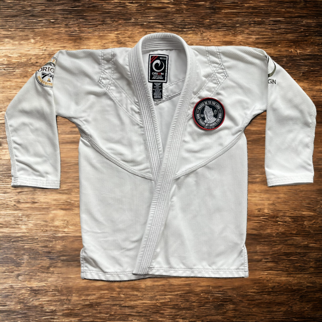 4in Patch with praying hands design and "PRAISE BE TO THE LORD WHO TRAINS MY HANDS FOR WAR" text on a white gi