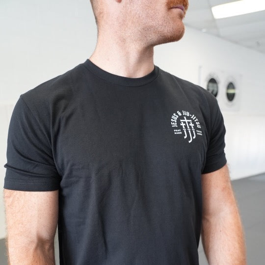 Person wearing a black t-shirt with a JJJ logo on the chest